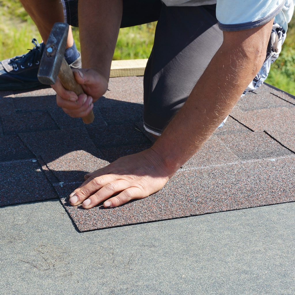 roofer nailing shingles on roof